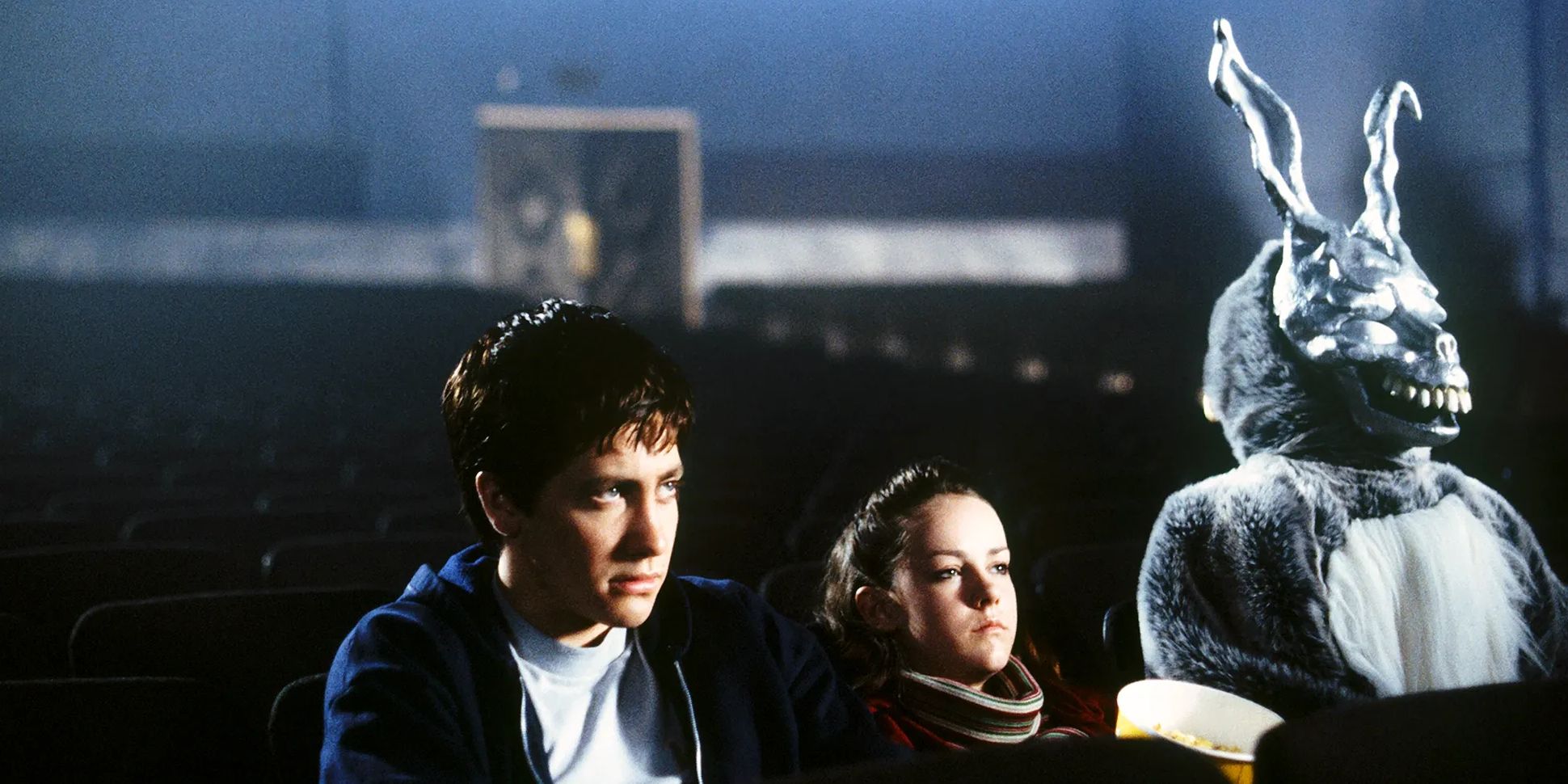 Donnie Darko sits in a movie theater with Frank the Rabbit