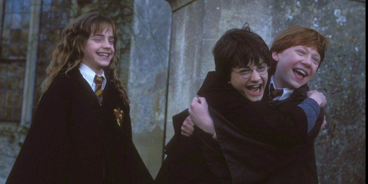 Hermione laughing as Ron and Harry hug from Harry Potter