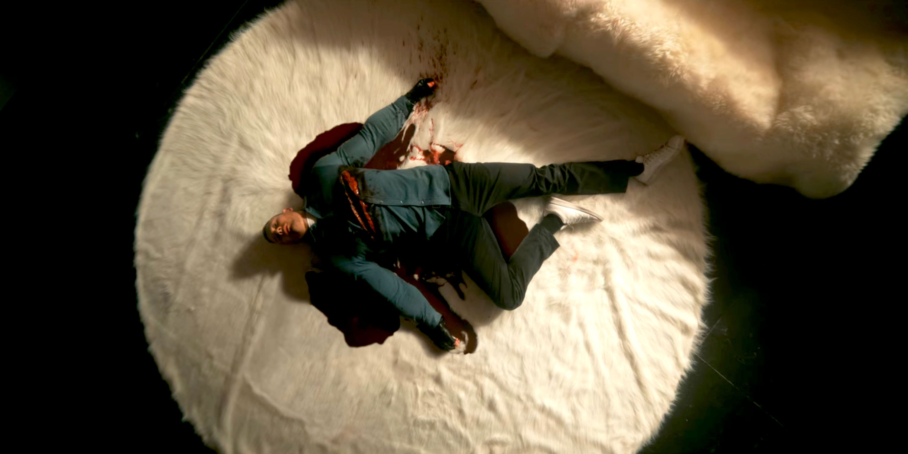 Luther lying dead on a white rug, blood pooling out from above both of his shoulders