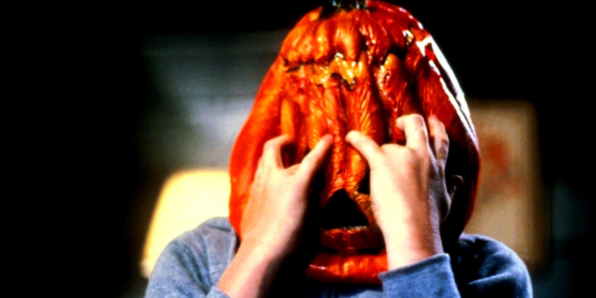 A person reaches for the pumpkin mask on his head in Halloween III