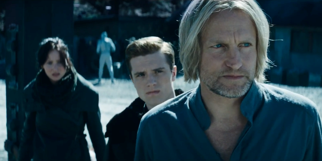 Haymitch, Peeta, and Katniss standing outside looking upset in The Hunger Games.