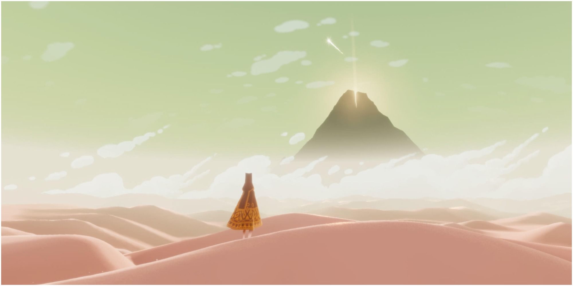 A still from Journey, a cloaked figure stands in the desert facing a glowing mountain