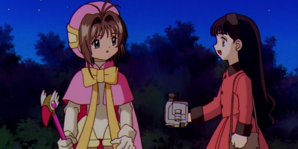 Cardcaptor Sakura in a pink dress while Tomoyo holds a camera in Cardcaptor Sakura.