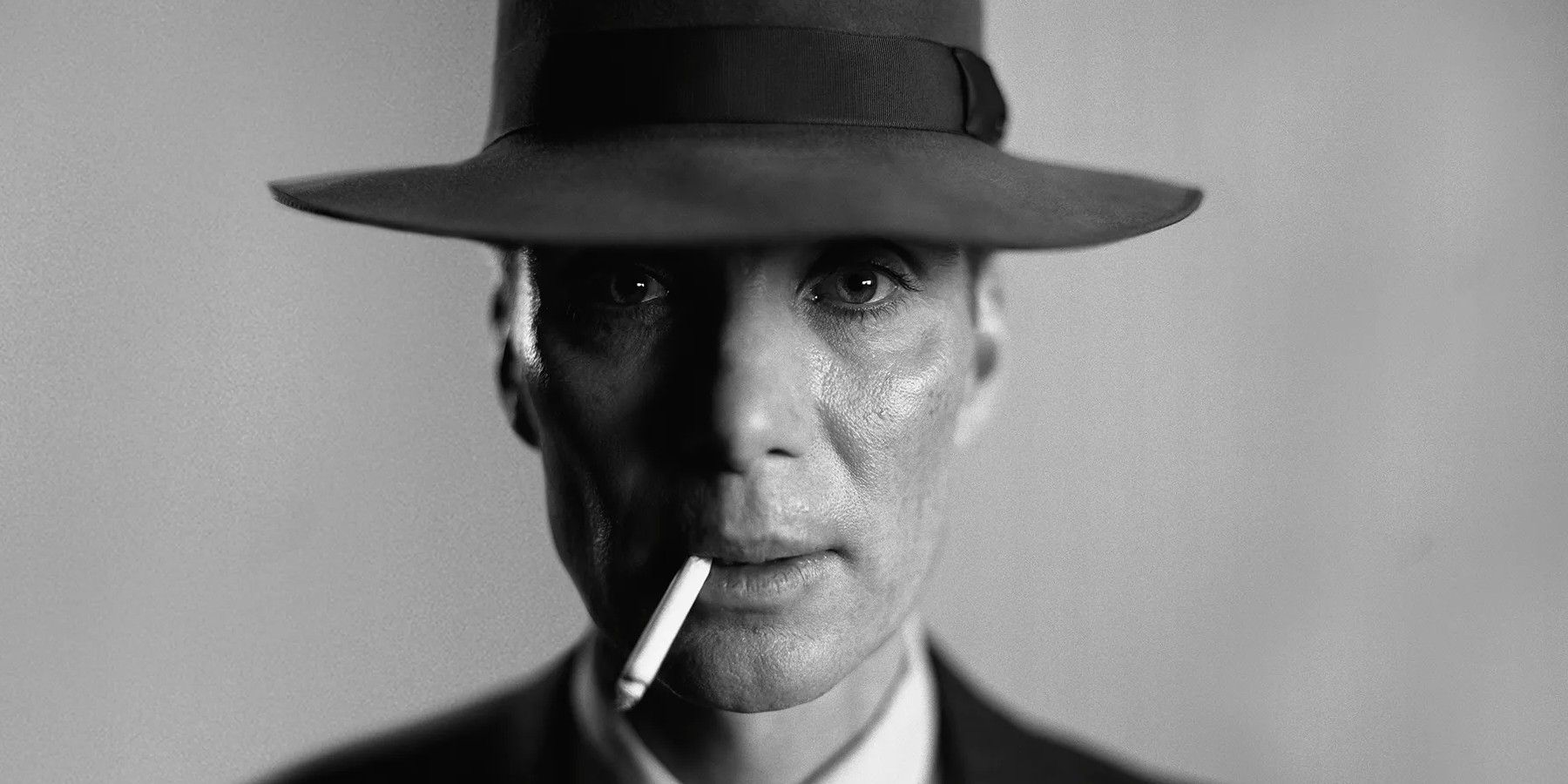 Cillian Murphy smokes a cigarette staring into the camera in Oppenheimer