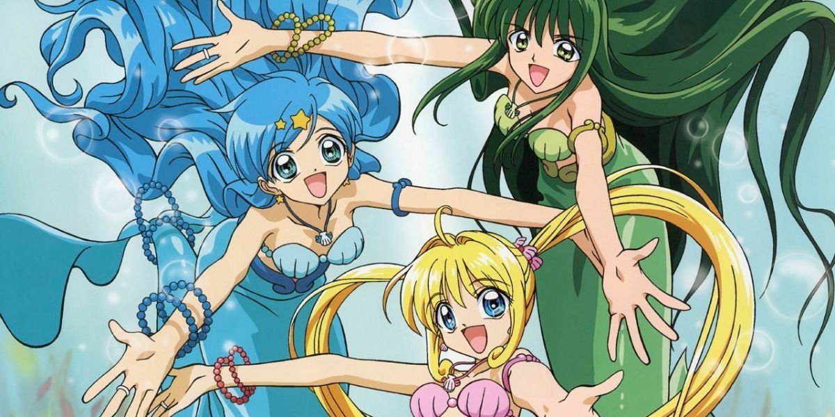 Image features a visual from Mermaid Melody Pichi Pichi Pitch: (From left to right) Hanon (long, blue hair and mermaid fins), Lucia (long, blonde pigtails and pink mermaid fins), and Rina (long, green hair and mermaid fins).