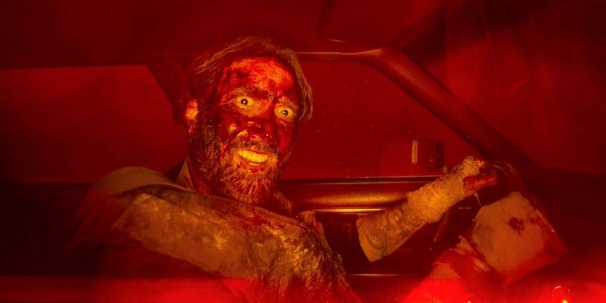 Nick Cage looking at the camera while driving a bloody car
