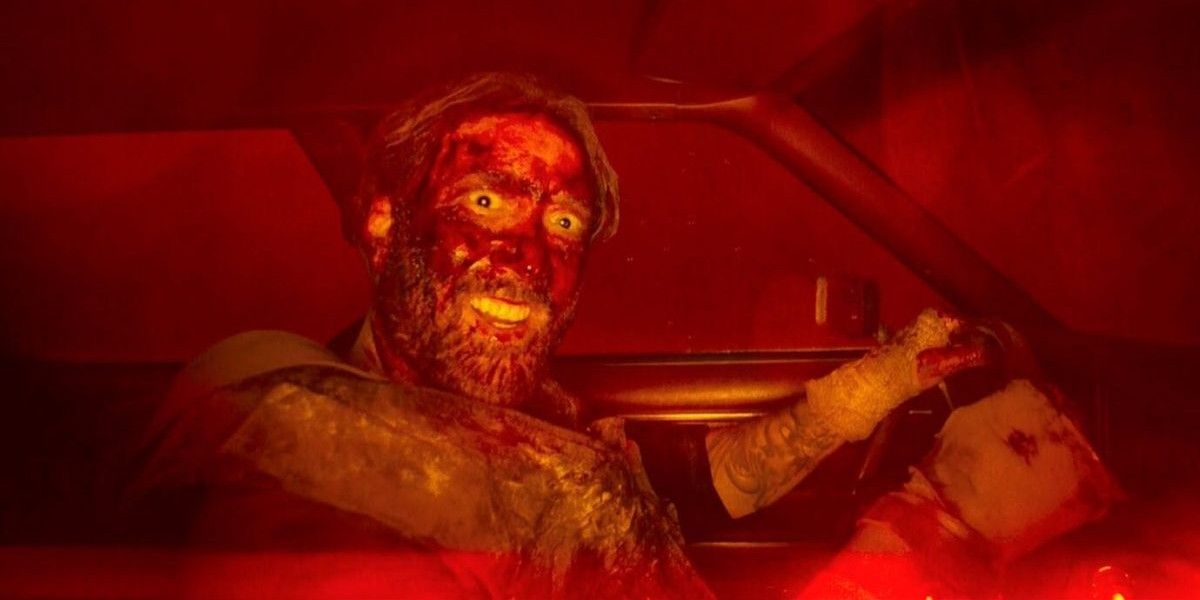 Nic Cage leers at the camera, driving a car, covered in blood, in Mandy