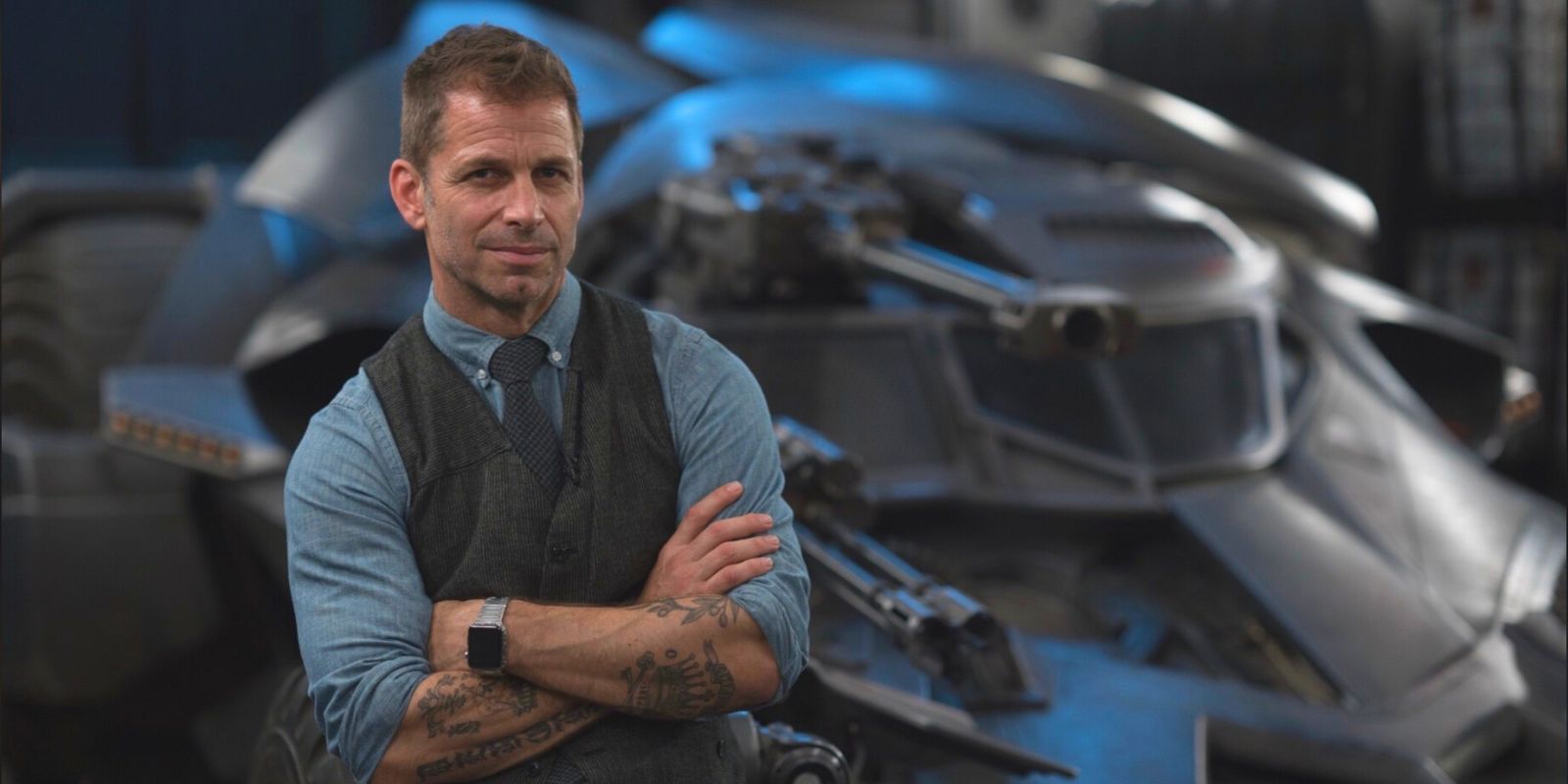 Zack Snyder posing in front of a tank