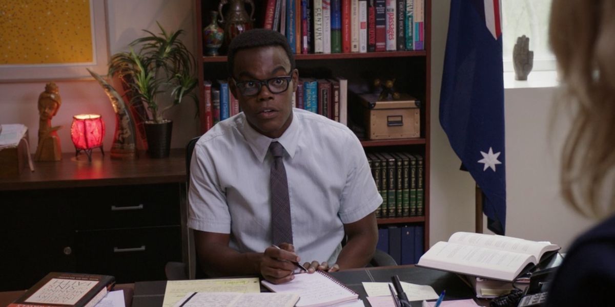 Chidi, interpretado por William Jackson Harper, sentado em sua mesa em The Good Place.