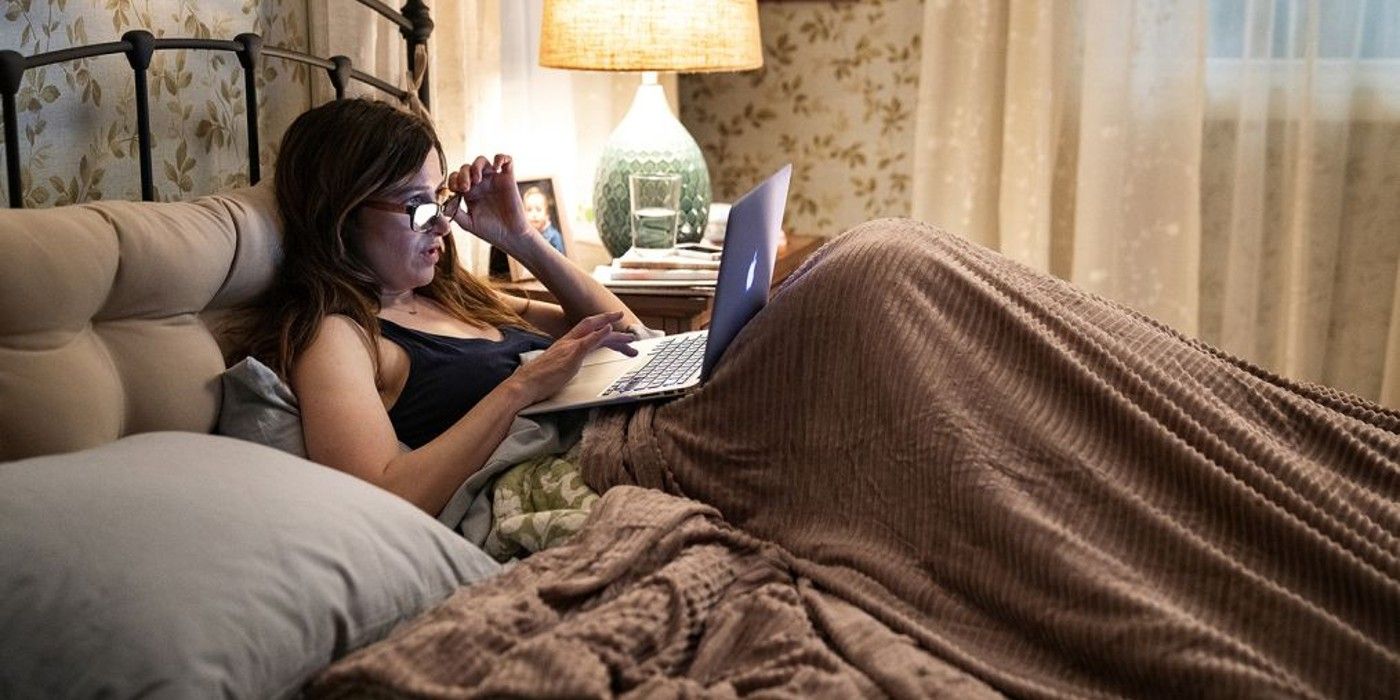 Mrs Fletcher star Kathryn Hahn in bed and looking at her laptop.