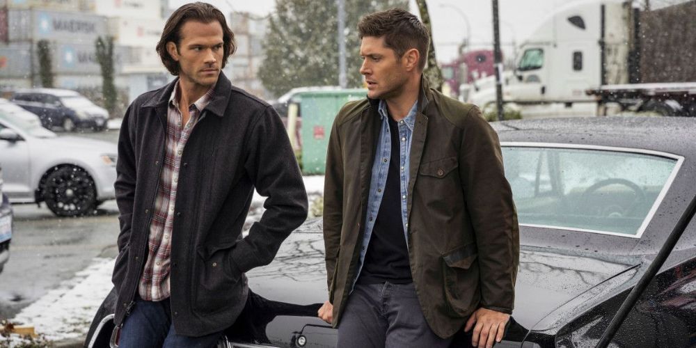 Sobrenatural todavía con Sam y Dean Winchester apoyados contra un auto.