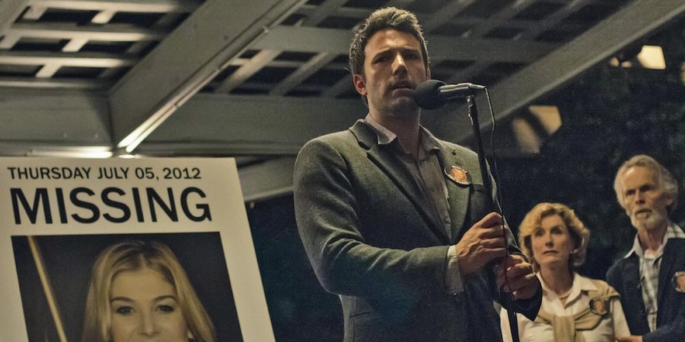 Nick Dunne stands by a poster of his missing wife Amy in Gone Girl