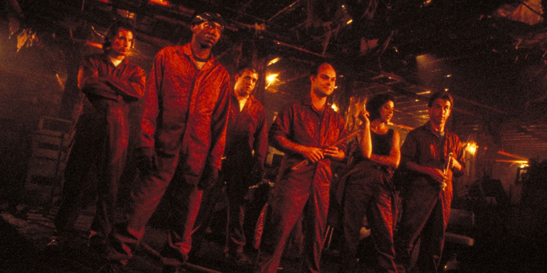 The characters of Stephen King's Graveyard Shift standing in formation in worker jumpsuits.