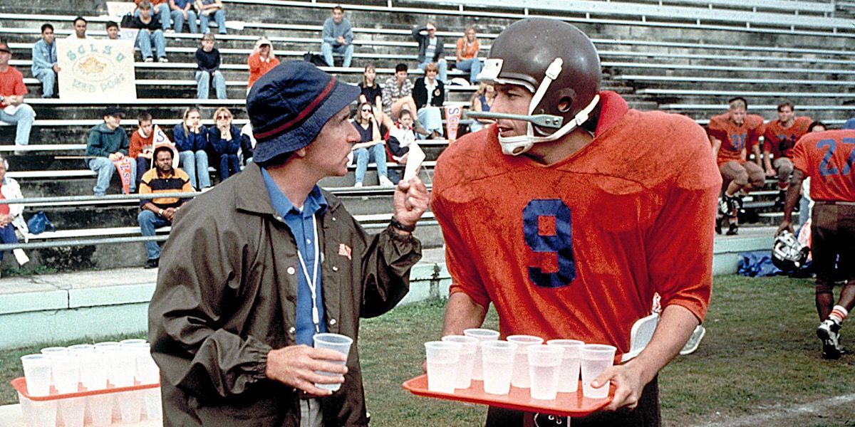 Bobby Boucher is holding water and speaking with the coach in The Waterboy