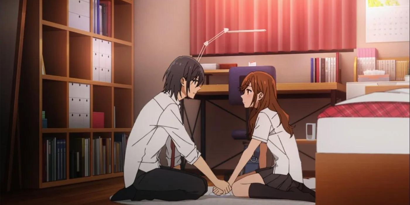 Hori and Miyamura holding hands on the bedroom floor in Horimiya.