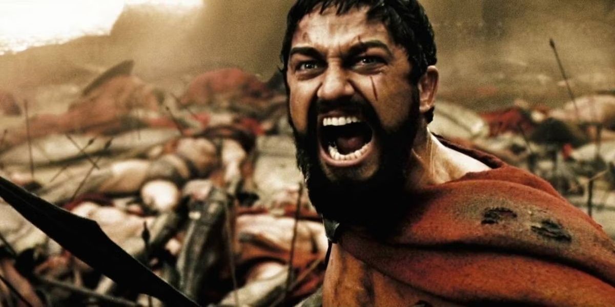 Gerard Butler as Leonidas I, yelling during the middle of a battle, fallen Spartans lay behind him.