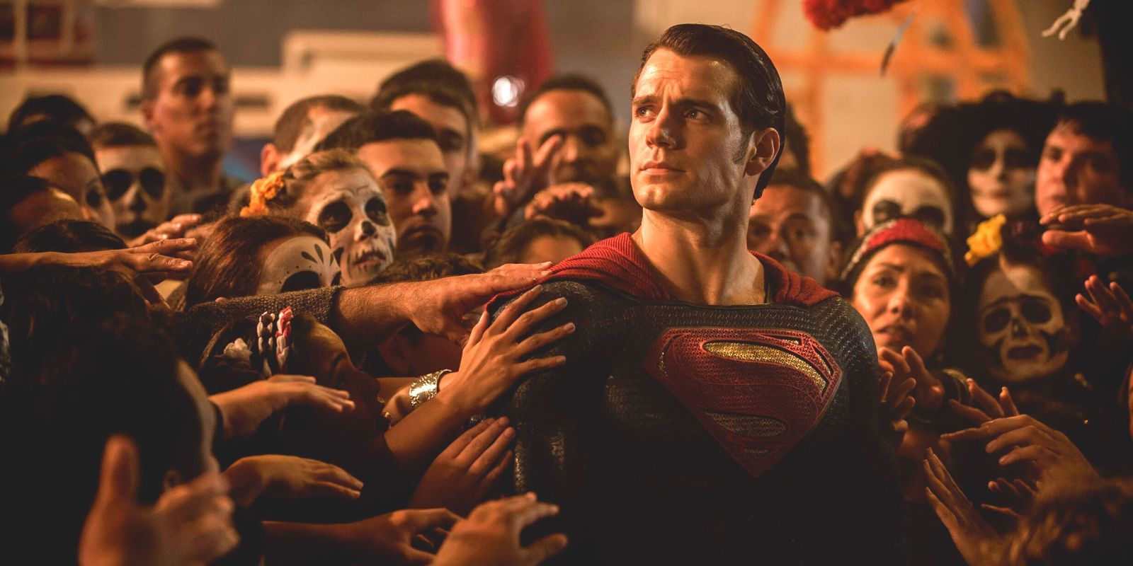 Henry Cavill's Superman surrounded by civilians reaching out to touch him.