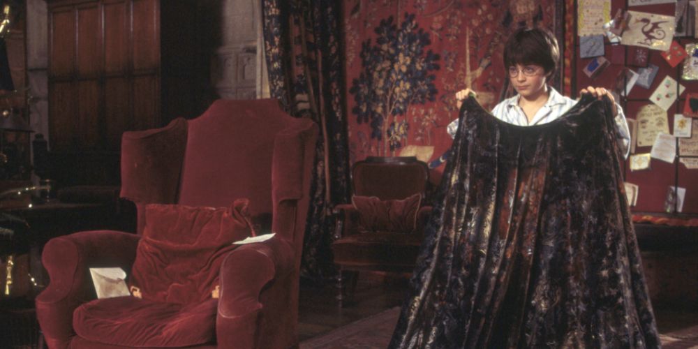 Harry holds the invisibility cloak in Harry Potter.