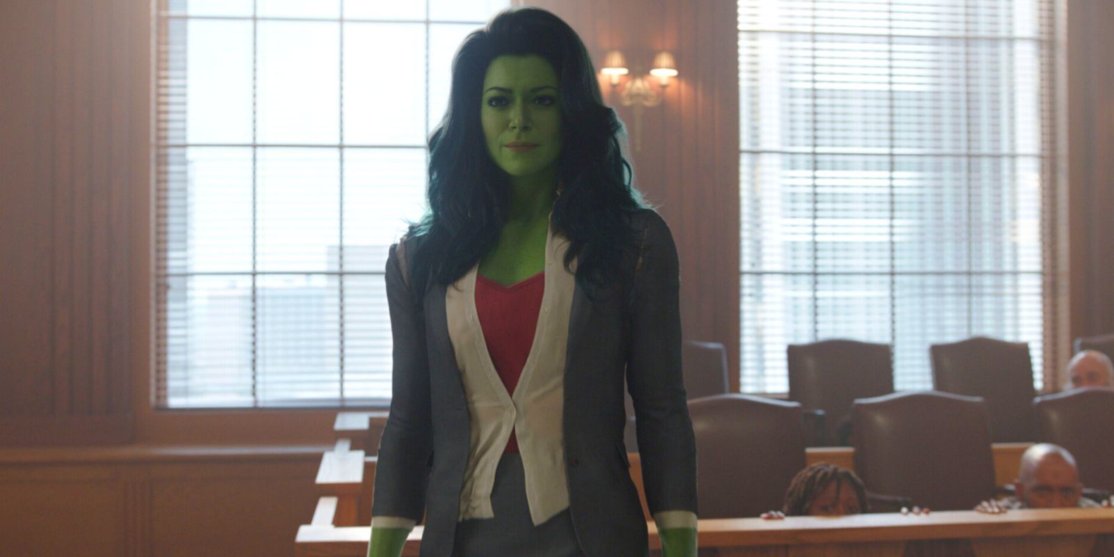 She-Hulk stands in a suit in a court room.