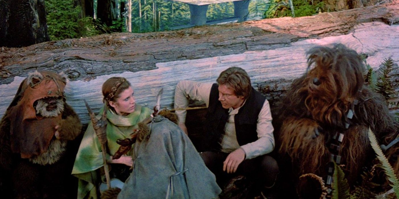 Wicket com Leia, Han e Chewbacca se escondendo atrás de uma árvore caída em Star Wars: Return of the Jedi.