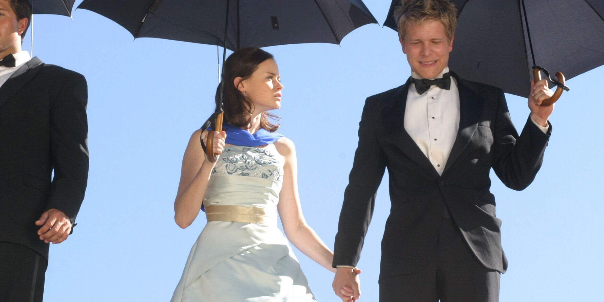 Rory and Logan in formal attire holding black umbrellas in Gilmore Girls