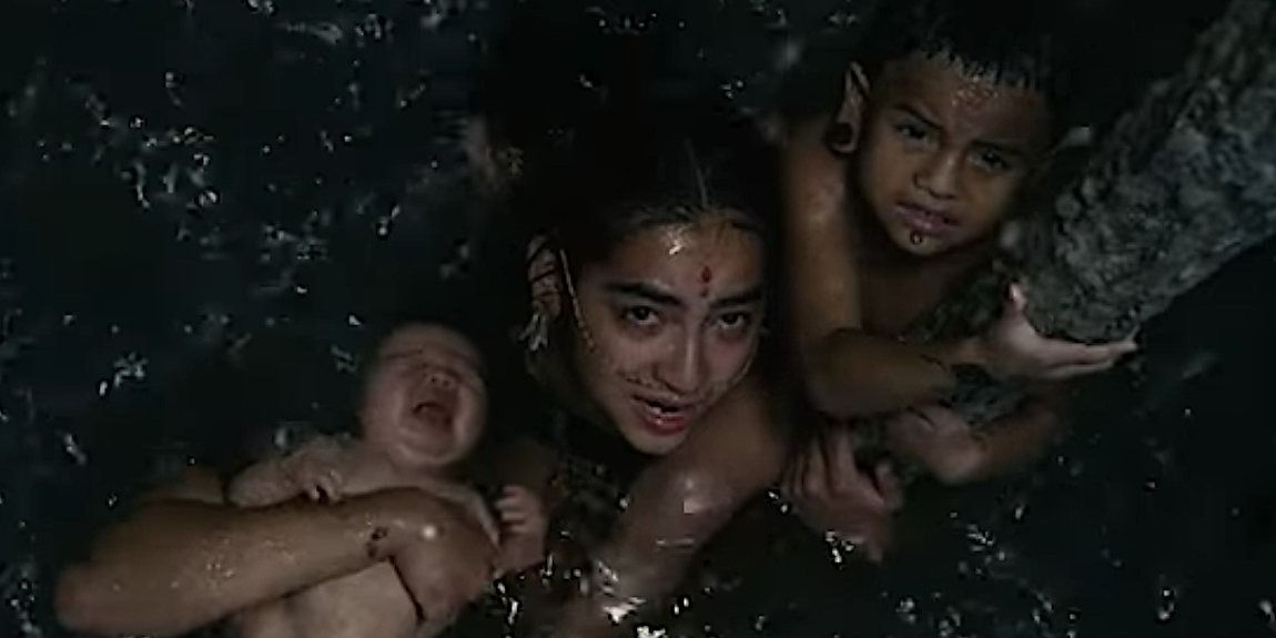 Six holds her newborn  baby and her other son next to her while they are trying to stay afloat in a flooded cavern - Apocalypto