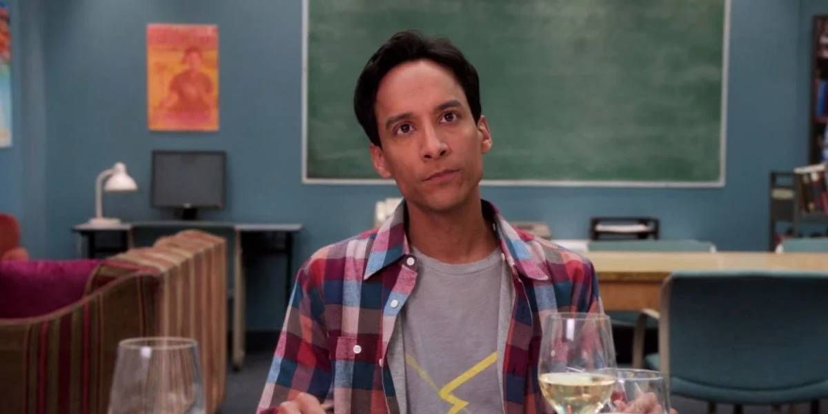 Danny Pudi drinks a bottle of wine in a room during Community