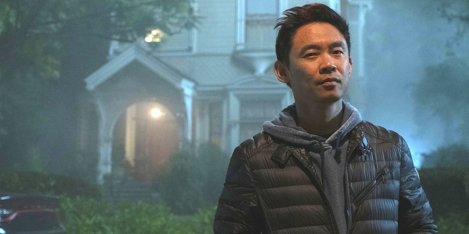 Director James Wan standing in front of a spooky house