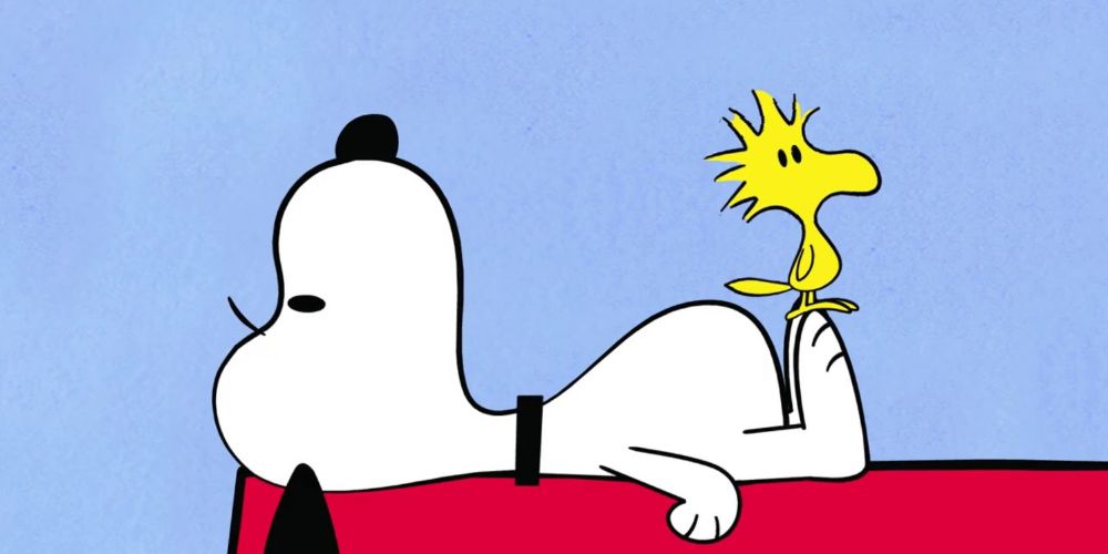 Snoopy and Woodstock lay on Snoopy's Doghouse
