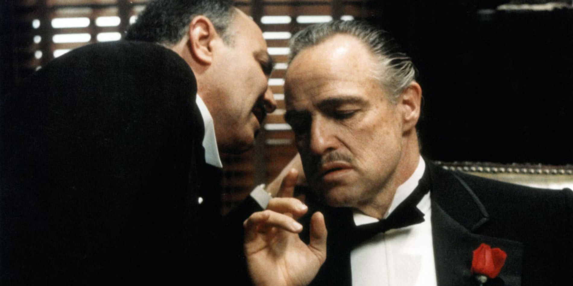 Bonasera whispers to Don Corleone as he sits in his chair