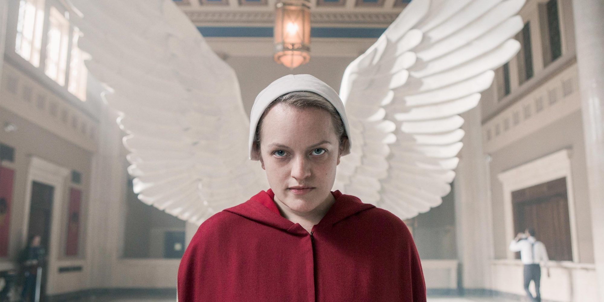 A still from The Handmaid's Tale of June staring into the camera with angel wings behind her