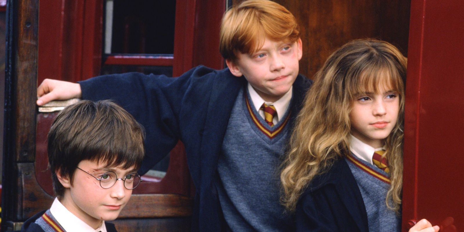 Harry Potter, Ron Weasley and Hermione Granger standing at the door of the Hogwarts Express