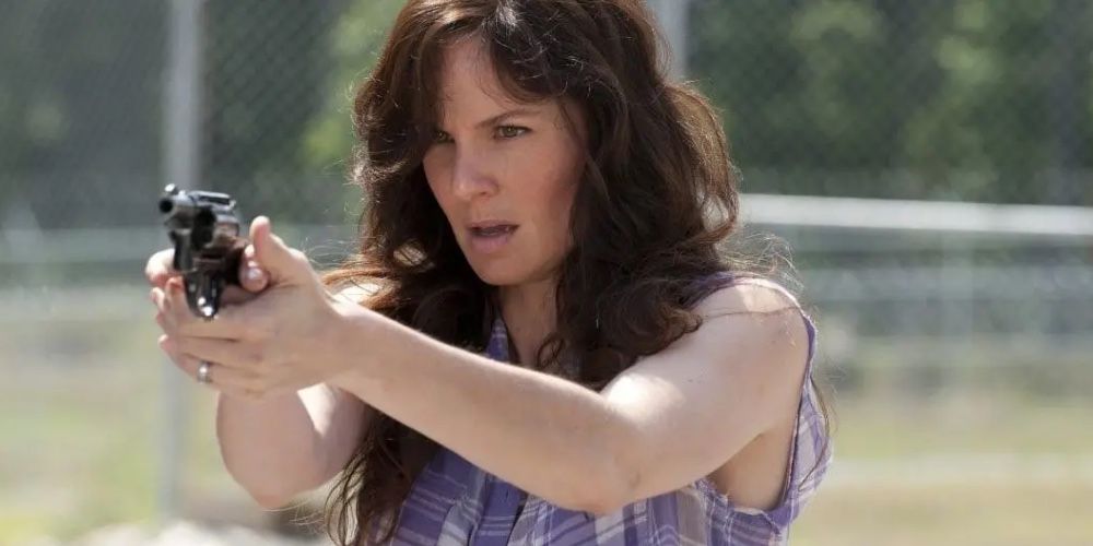 Lori Grimes holds a gun out on front of her in a field in The Walking Dead