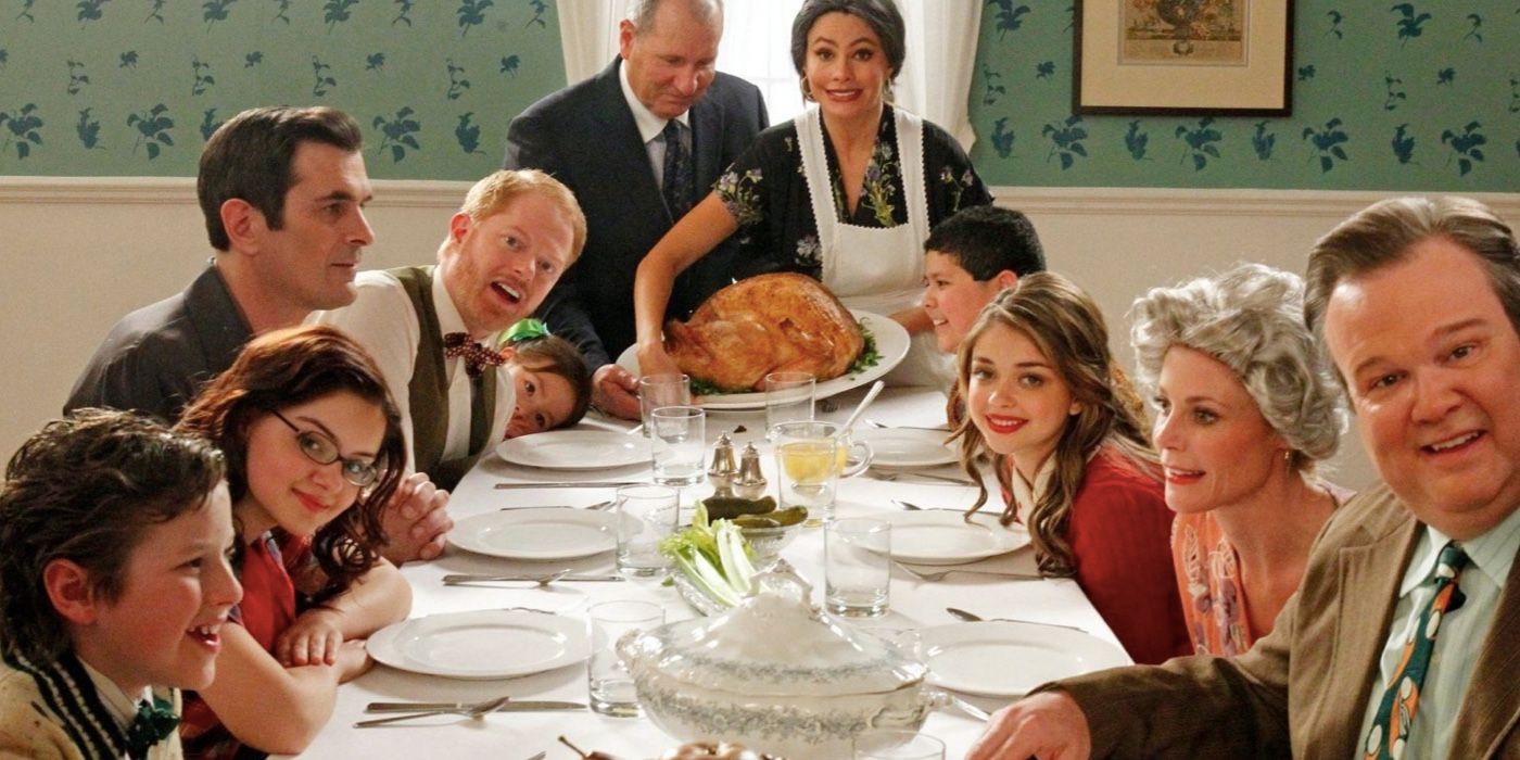 The characters in Modern Family smile for a Thanksgiving photo at the table