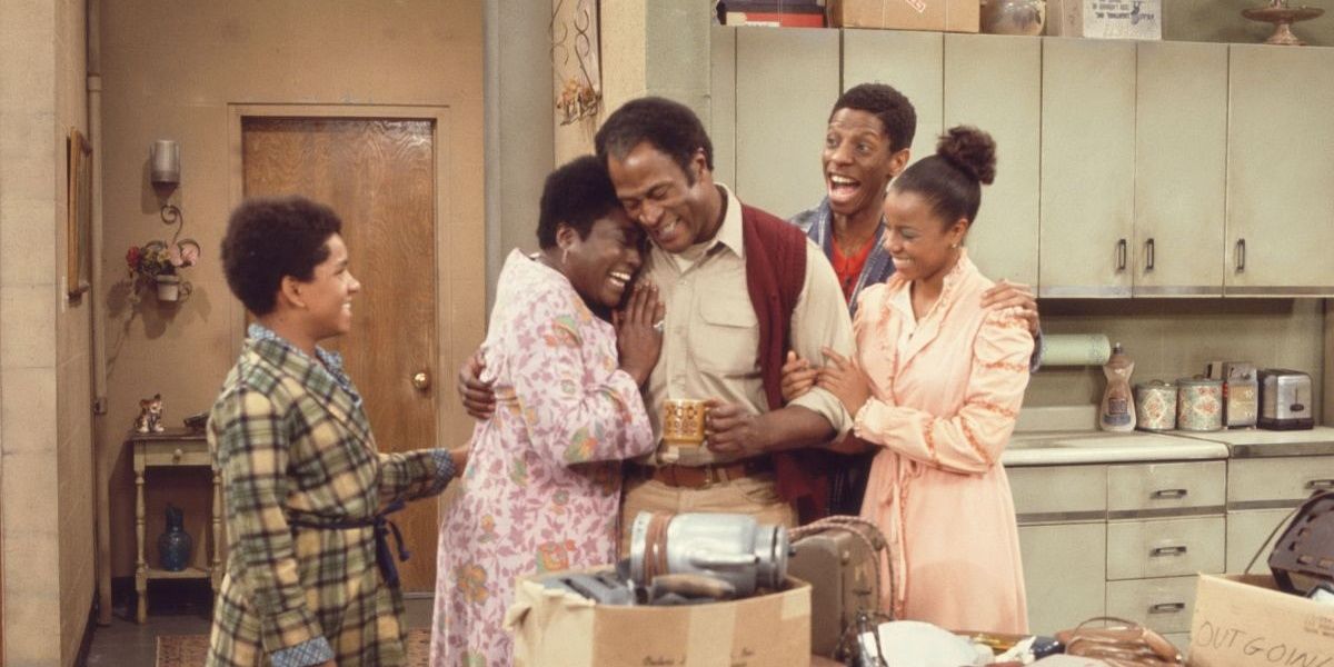 A family hugs in the kitchen in Good Times.