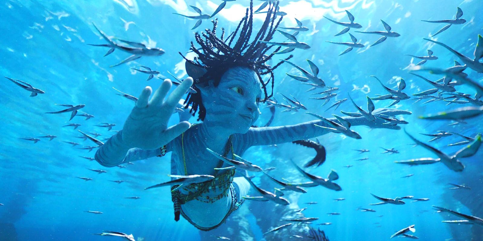 A young Na'vi child swimming in the ocean in a shoal of fish