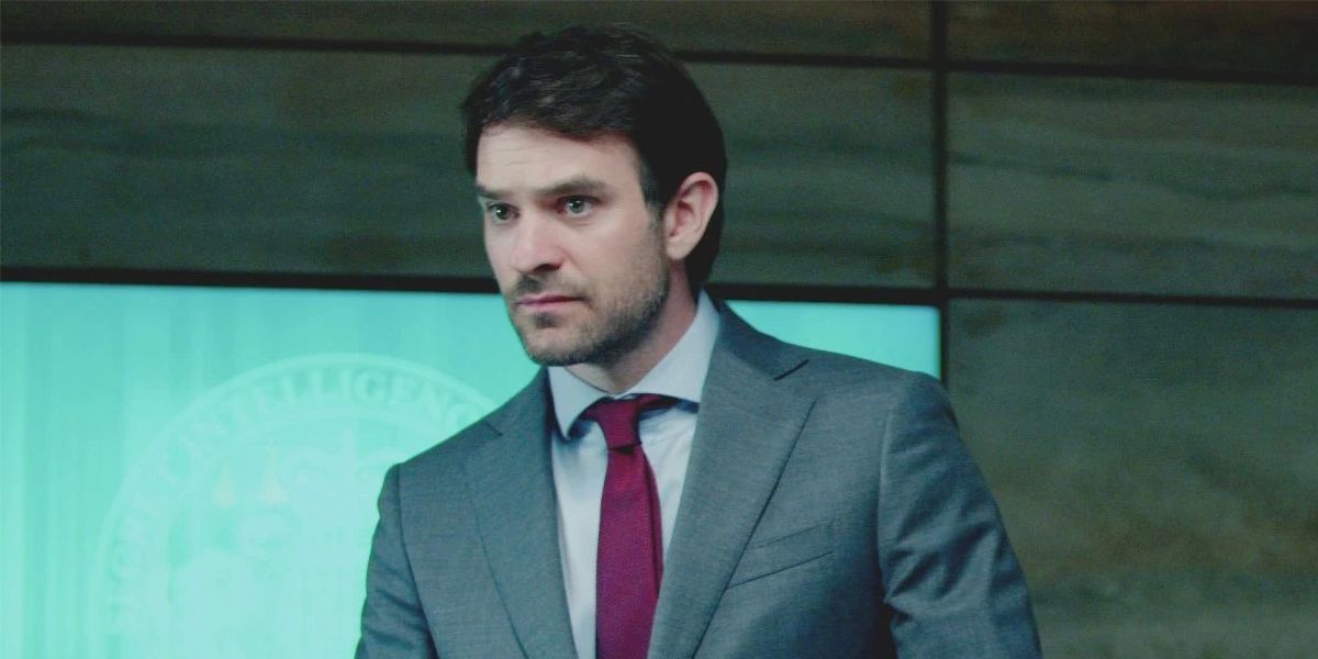 Charlie Cox standing in a suit in Treason
