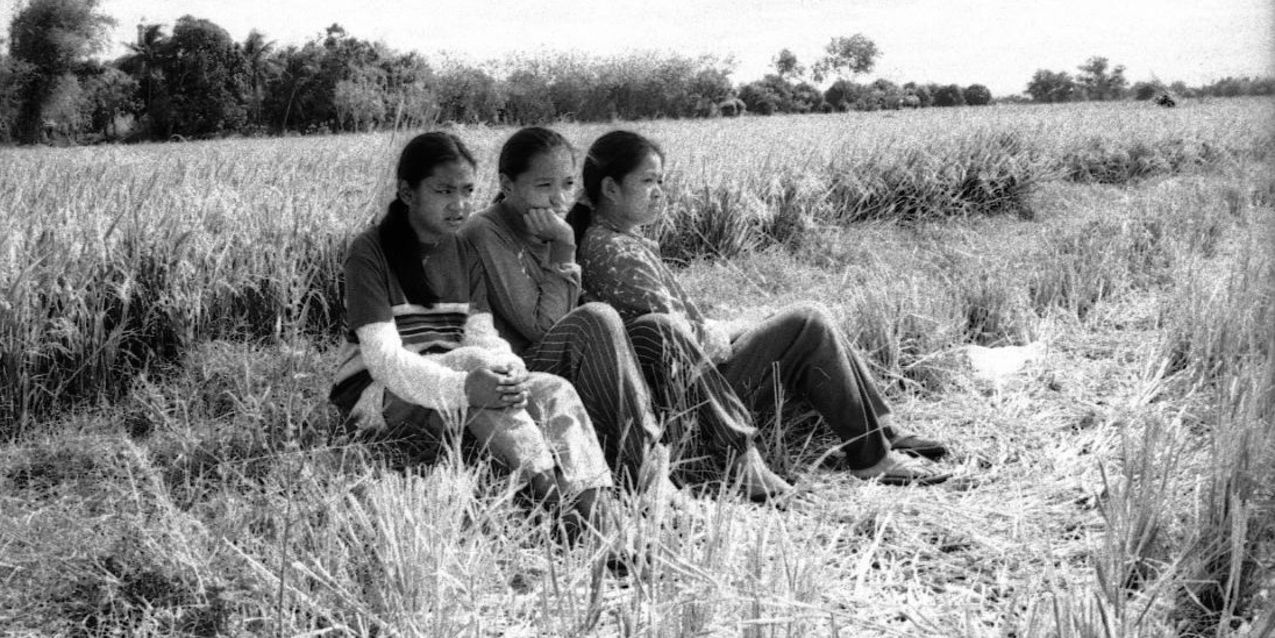 Three siblings sit together in the fields in Evolution Of A Filipino Family