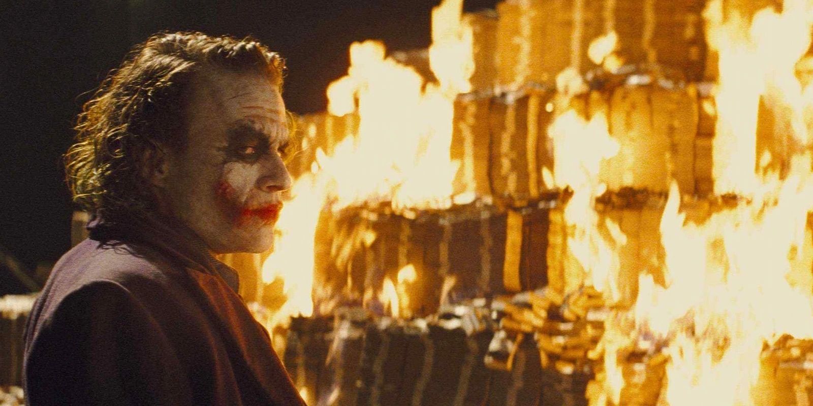 Heath Ledger como Coringa diante de uma pilha de dinheiro em chamas em O Cavaleiro das Trevas.
