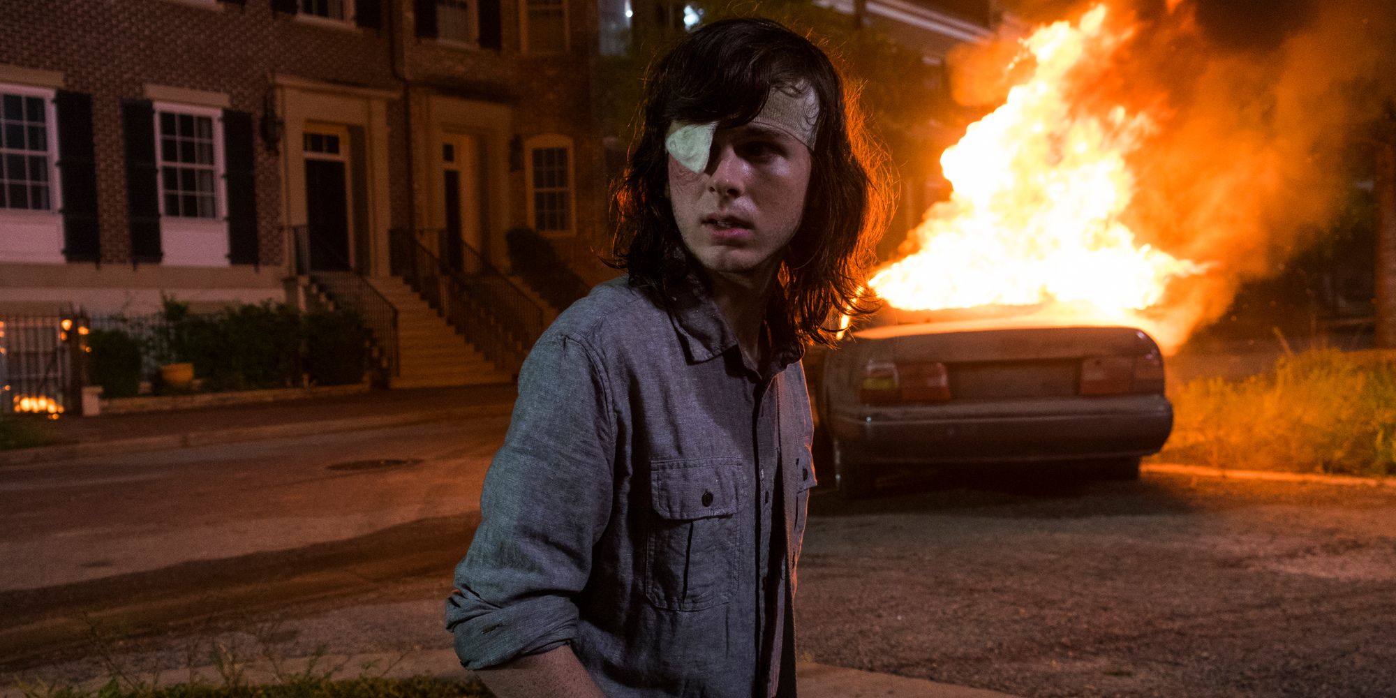 Carl (Chandler Riggs) is distraught with a car burning in the background during the Savior's attack on Alexandria in "How It's Gotta Be" in The Walking Dead