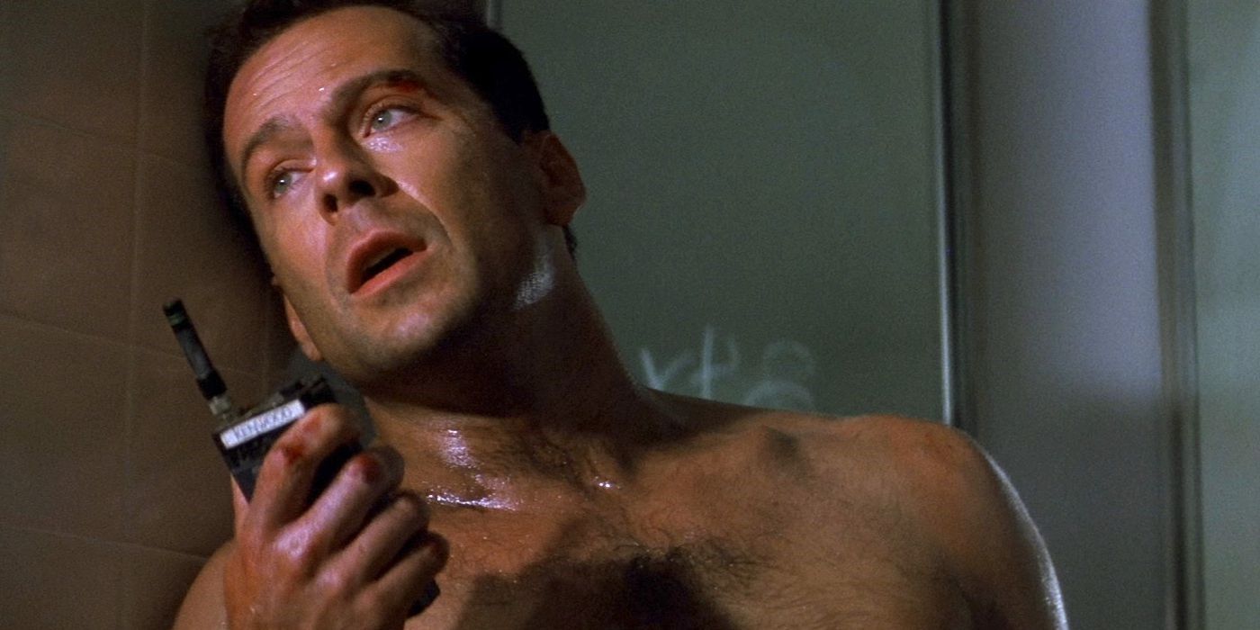 A sweaty and shirtless John McClane holding a walkie in Die Hard (1988).