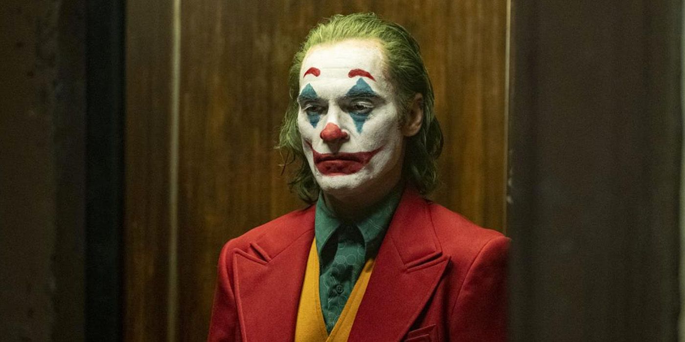 Joaquin Phoenix as Arthur Fleck standing in a hallway in full makeup in Joker.
