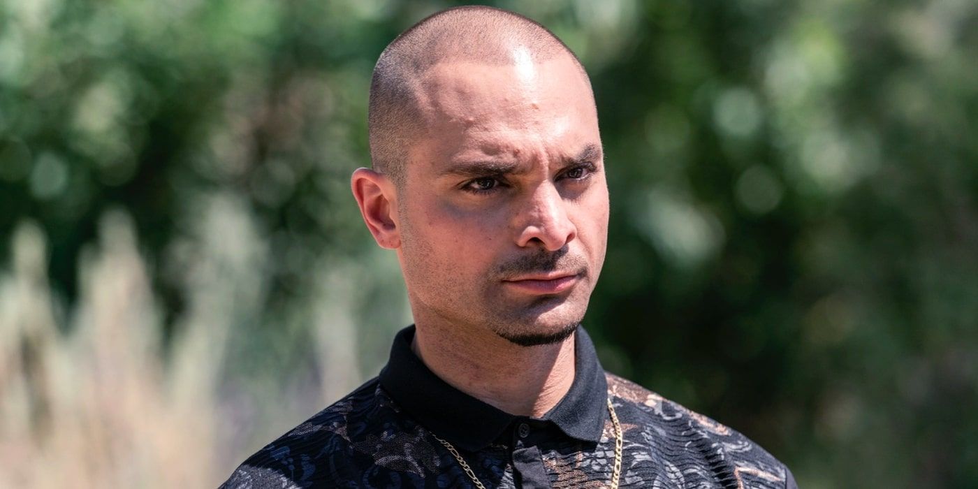 Better Call Saul's Nacho (played by Michael Mando) stands in a field with a threatening expression on his face