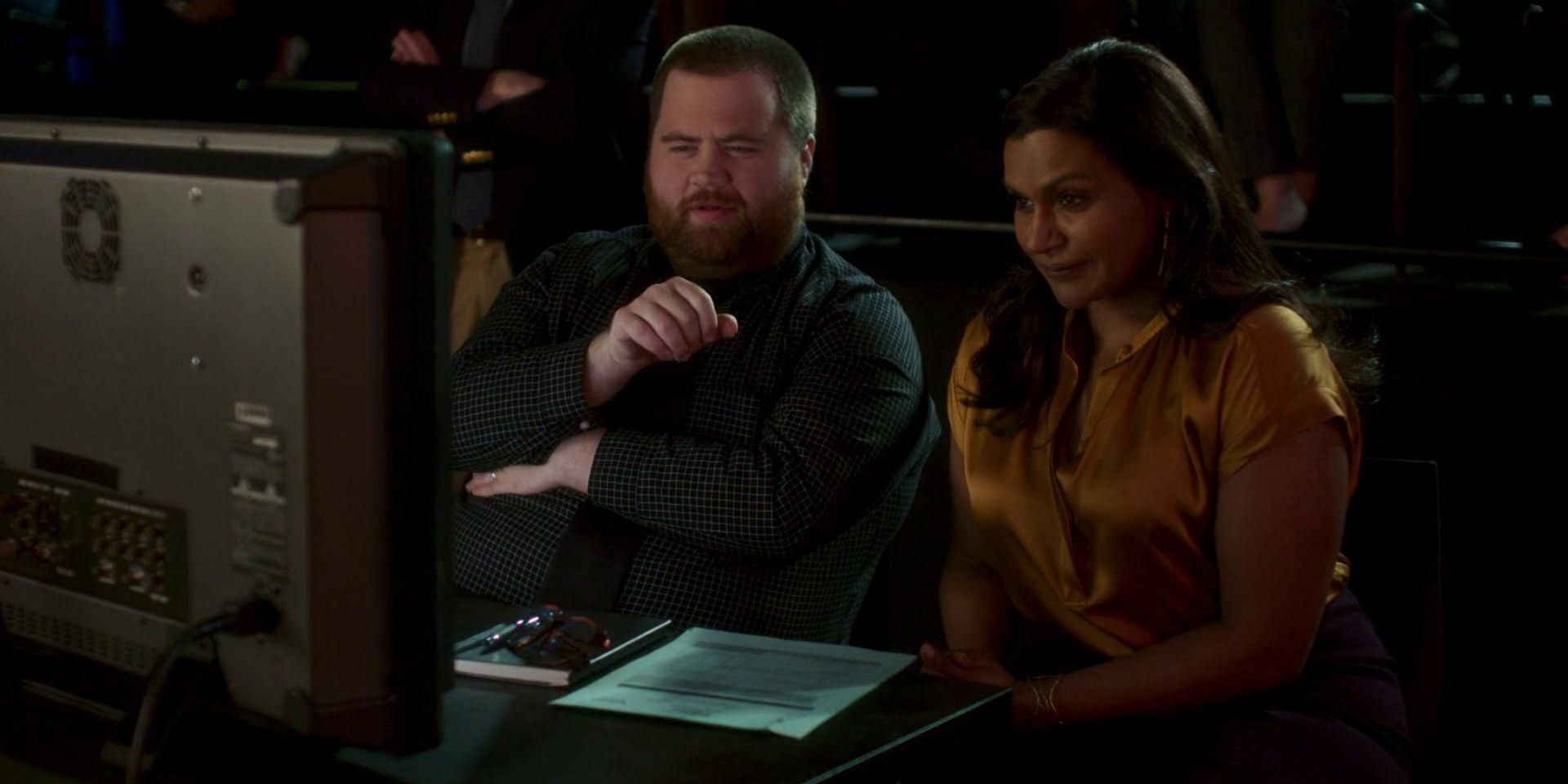 Paul Walter Hauser and Mindy Kaling looking at a TV in Late Night