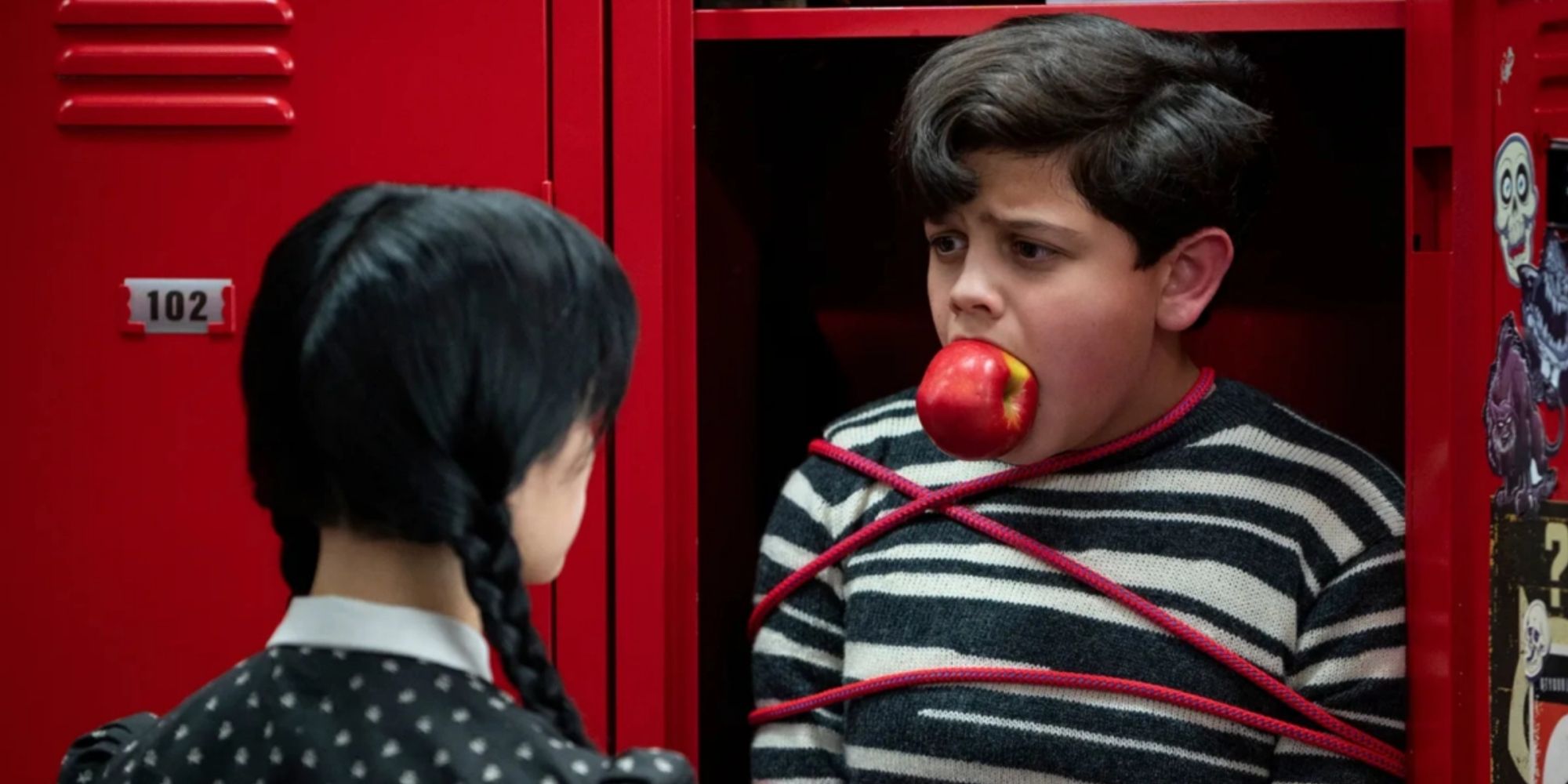 Pugsley on Wednesday Netflix, stuffed in a locker and tied up with an apple in his mouth.