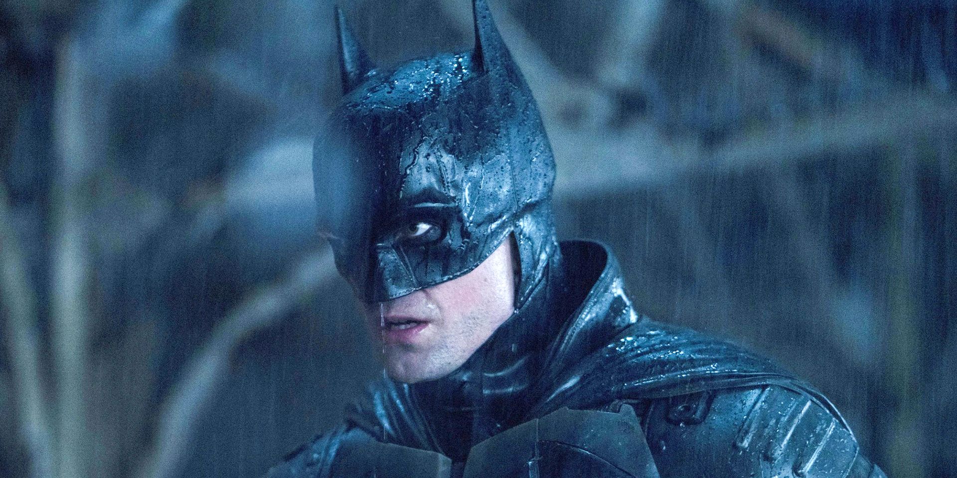 Robert Pattinson as Bruce Wayne in The Batman stands in the rain