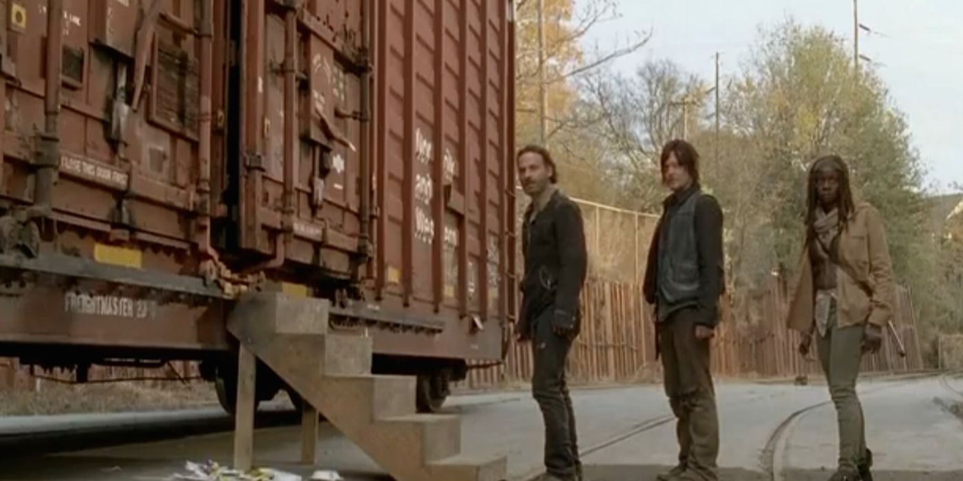 Rick, Daryl, and Michonne in a line outside a train car in The Walking Dead. 