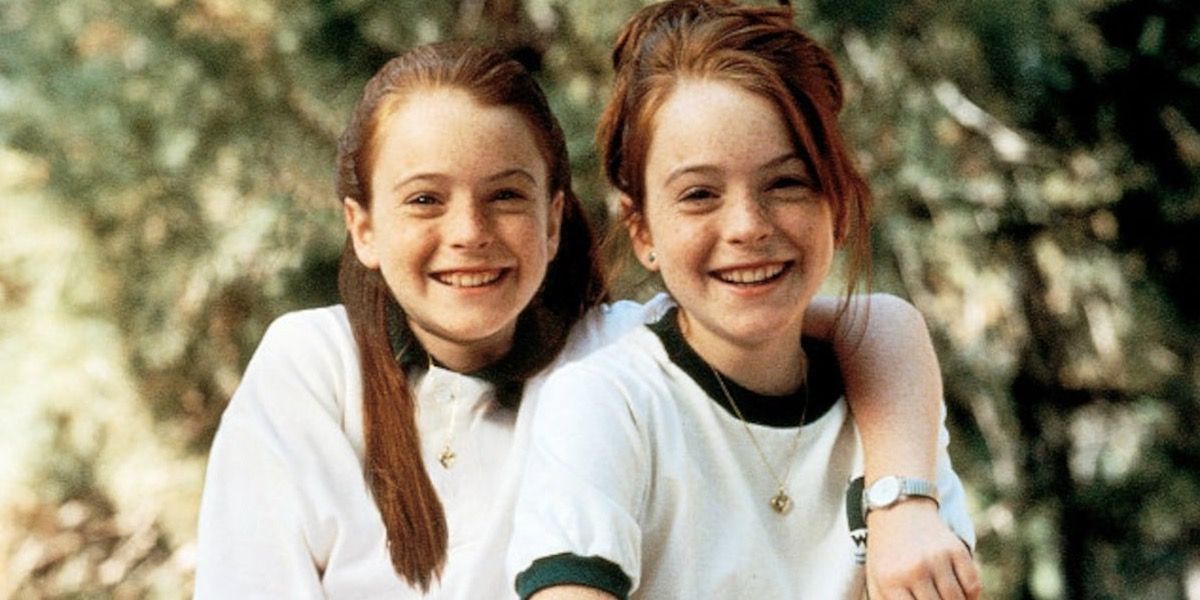 Annie and Hallie (Lindsay Lohan) are sitting together and smiling at summer camp. 