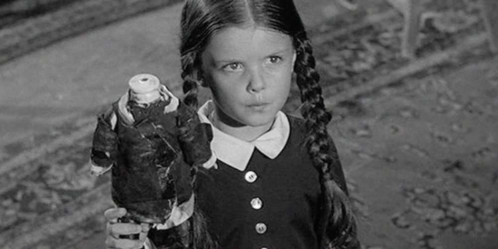 Lisa Loring's Wednesday Addams holding a headless doll in The Addams Family