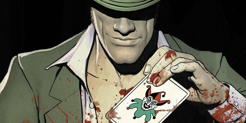 The Riddler holds a playing card that says Joker.  He and the card are both covered in blood.